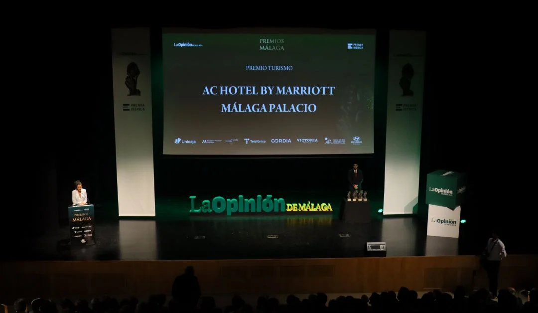 Premiados en el escenario del AC HOTEL BY MARRIOTT MÁLAGA PALACIO y escenario con presentadora.